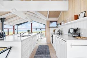 a white kitchen with a view of the ocean at 12292-Sjaellands-Odde-Lyngbugten-10 in Yderby +21 photos