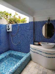 a blue tiled bathroom with a tub and a sink at Brassiere Beach Hotel in Baanphakrimlay 