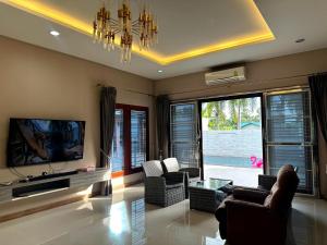 a living room with a couch and chairs and a tv at The Horizon Villa Songkhla in Ban Mai