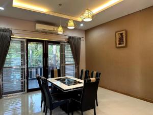 a dining room with a table and chairs and windows at The Horizon Villa Songkhla in Ban Mai
