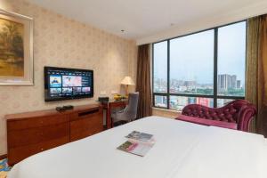 a hotel room with a bed and a flat screen tv at Oriental Glory Hotel in Dongguan