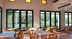 a dining room with tables and chairs and windows at Baan Nan Hotel in Nan