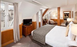 a hotel room with a bed and a television at Meliá Paris Vendôme in Paris