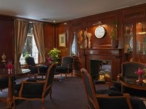 a room with a fireplace and chairs and a clock at Meliá Paris Vendôme in Paris
