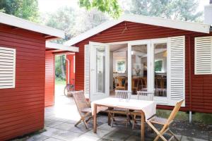 a red house with a table and chairs on a patio at 10033-1-Rorvig-Hjortevej-17 in Rørvig