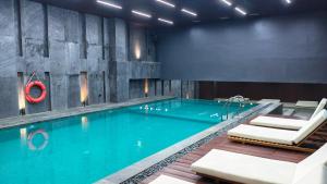 a large swimming pool with chairs and a swimming pool at Nusatu by ARTOTEL - Semarang in Semarang