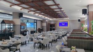 a dining room with tables and chairs in a restaurant at Nusatu by ARTOTEL - Semarang in Semarang