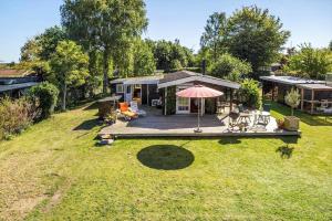 a house with a deck with an umbrella on a yard at FJ1401-Jaegerspris-Hovdiget-5 in Jægerspris