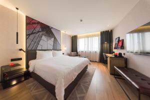 a hotel room with a large bed and a bench at Radisson RED Shanghai Wujiaochang Hotel in Shanghai