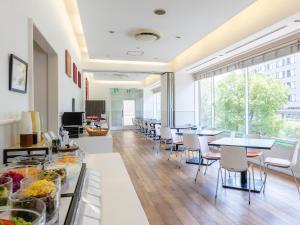 a cafeteria with tables and chairs and a large window at KOKO HOTEL Yokohama Tsurumi in Yokohama