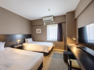 a hotel room with two beds and a flat screen tv at KOKO HOTEL Yokohama Tsurumi in Yokohama +54 photos