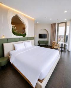 a bedroom with a large white bed and a living room at Solia Hill Hotel in Dong Hoi