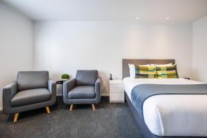a bedroom with two chairs and a bed at Braemar Motor Lodge in Palmerston North +38 photos