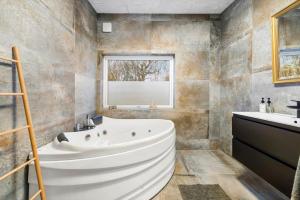 a bathroom with a large tub and a sink at FJ1202-Jaegerspris-Lille-Engvej-7 in Jægerspris +21 photos