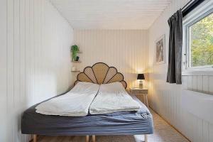 a bedroom with a bed with a wooden headboard and a window at FJ1404-Jaegerspris-Strandstien-17 in Jægerspris