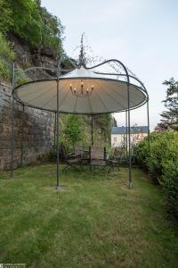 ein großer Regenschirm in einem Hof mit zwei Bänken in der Unterkunft Albergo-Toscana in Bad Schandau