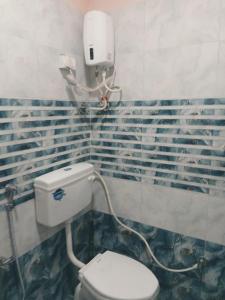 a bathroom with a toilet and a soap dispenser on the wall at Samarth Villa in Akalkot