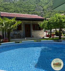 a large blue swimming pool in front of a house at Small Stone Cottage in Virpazar