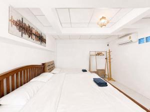 a room with a large white bed in it at Gao Check in Phala Beach Front in Rayong
