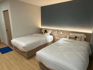 a hotel room with two beds with white sheets at Tokyo Hotel in Ubon Ratchathani