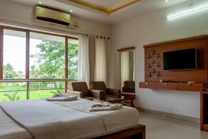 a hotel room with a bed and a tv at Captains Cabin, Alleppey- A Premium Backwater Mansion in Alleppey