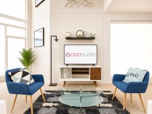 a living room with a tv and two chairs and a table at Upscale 3BR Penthouse by CozySuites in Indianapolis