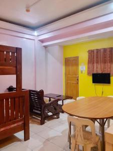 a living room with a table and a yellow wall at ASHBURN'S TRANSIENT BAGUIO - BASIC SLEEP and GO, LIMITED PAY PARKING, SELF SERVICE in Baguio