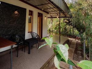 a patio with two chairs and a table on a house at SpiceBuds FarmStay - Ramakkalmedu in Idukki