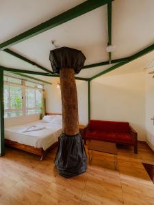 a room with a bed with a tree in it at SpiceBuds FarmStay - Ramakkalmedu in Idukki