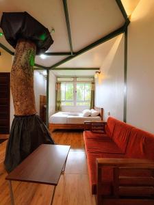 a living room with a red couch and a bed at SpiceBuds FarmStay - Ramakkalmedu in Idukki