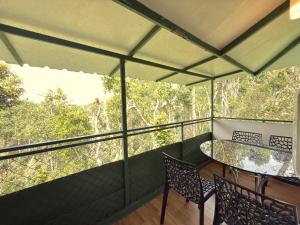 a balcony with a table and chairs and trees at SpiceBuds FarmStay - Ramakkalmedu in Idukki