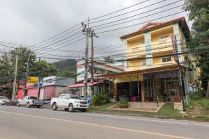a building on the side of a street with cars parked in front at Pachumas Hotel in Karon Beach