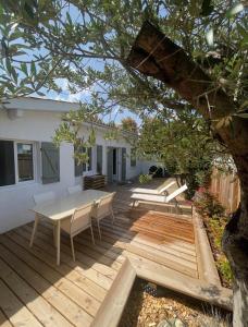 a wooden deck with a table and chairs on it at La Cabane 21, Maison, Andernos-Les-Bains in Andernos-les-Bains