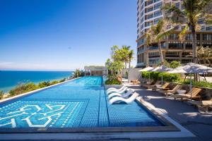 a swimming pool with lounge chairs and the ocean at Mandala Twilight Haven 5 Star in Phan Thiet