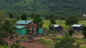 a group of buildings in a field with trees at Cow Barn Cafe and Lodge Preah Vihear in Phumĭ Nhông