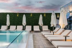 a pool with white chairs and umbrellas at Caption By Hyatt Chattanooga Downtown in Chattanooga