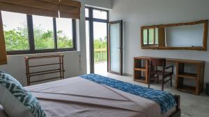 a bedroom with a bed and a desk and a mirror at Kudakalliya Beach Houses in Arugam Bay +28 photos