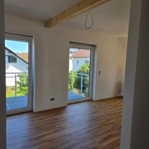 an empty living room with two large sliding doors at schöne Neubau Ferienwohnung "Wiesent" mit Küche und Balkon in Forchheim