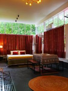 a bedroom with two beds and red curtains at Dheer- BnB at an Artist's Abode in Shānti Niketan