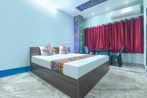 a bedroom with a bed with red curtains and a table at FabHotel Taj Palace in kolkata +24 photos