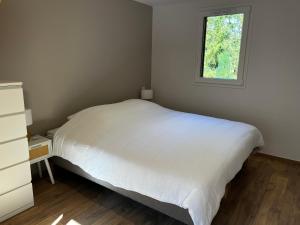 a bedroom with a white bed and a window at Chalet des Épicéas - babyfoot billard & PS in Gérardmer