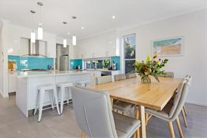 a dining room and kitchen with a wooden table and chairs at The Art House at Beachside in Yaroomba