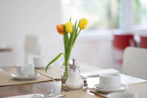 a table with a vase with yellow flowers in it at Gästehaus Schechter in Uhldingen-Mühlhofen