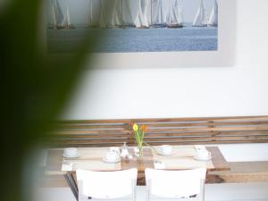 a table with white chairs and sailboats in the background at Gästehaus Schechter in Uhldingen-Mühlhofen