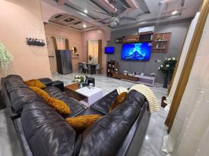 a living room with a leather couch and a tv at Royal Zam Résidence in Ouagadougou