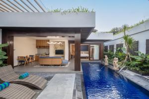 an outdoor living area with a swimming pool and a house at THE SAND Suites & Villas in Ngurah Rai International Airport
