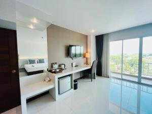 a room with a desk with a television and a couch at Chaisaeng Villa in Sing Buri