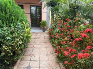 a garden with red flowers and a walkway at Royal Zam Résidence in Ouagadougou
