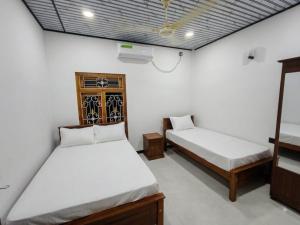 two beds are in a room with white walls at VIN Solara Farm Stay in Jaffna
