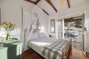 a bedroom with a bed and a window with a porch at Bellbird Rise Off-Grid Cottage in Conondale